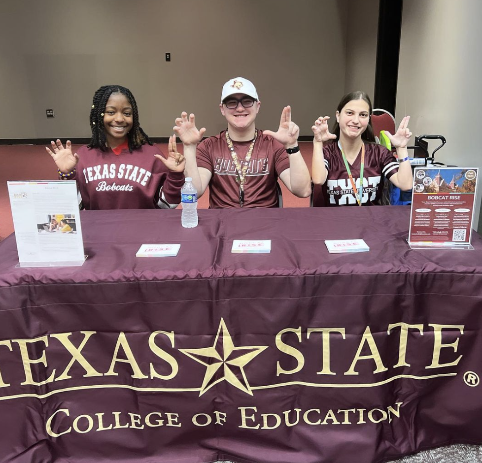 Three students from Bobcats RISE Program. They are sitting at a table with information on Texas State information.